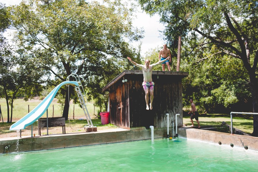 groom to be jumps into pool at family ranch in boerne before wedding day in San Antonio, Texas. Photo by Caitlin McWeeney Photography