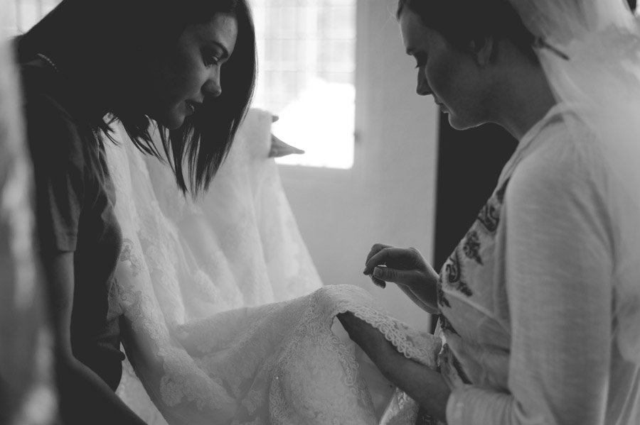 bride inspects her dress with a bridesmaid prior to her wedding
