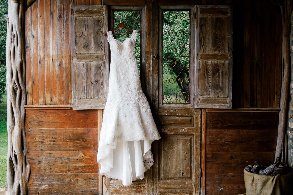 dress hanging on rustic iron wall in wimberley texas, old glory ranch dress shot, fall at old glory ranch, justin alexander rustic wedding dress