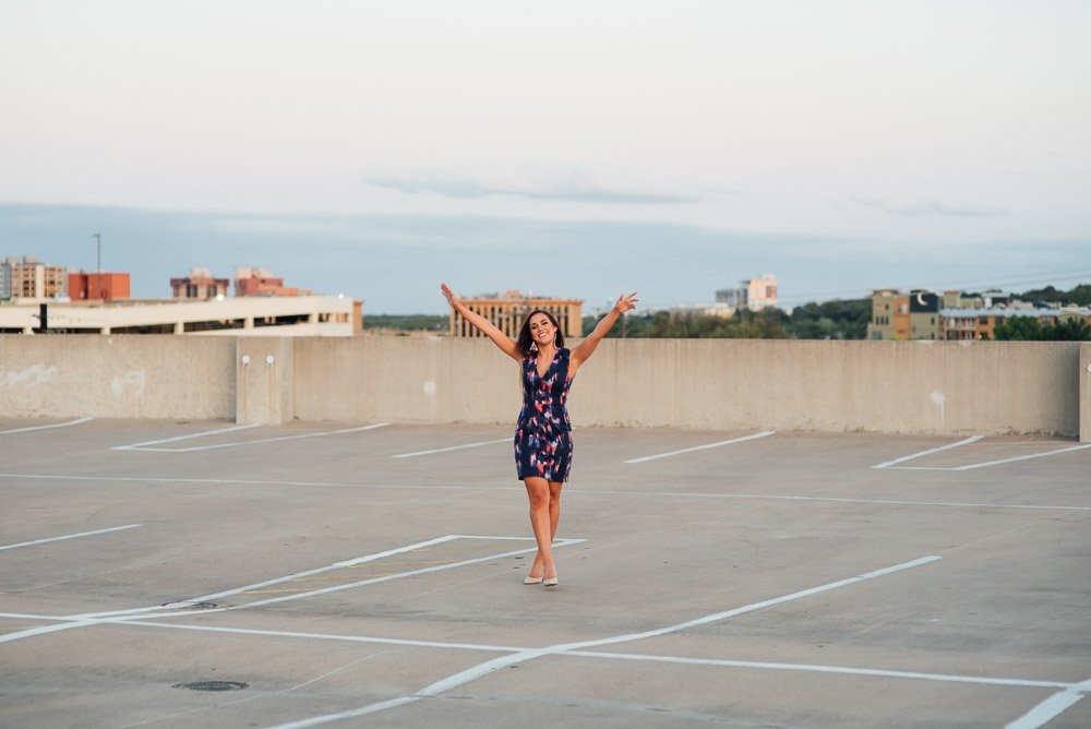 girl on top of an austin parking garage laughing during graduation pictures