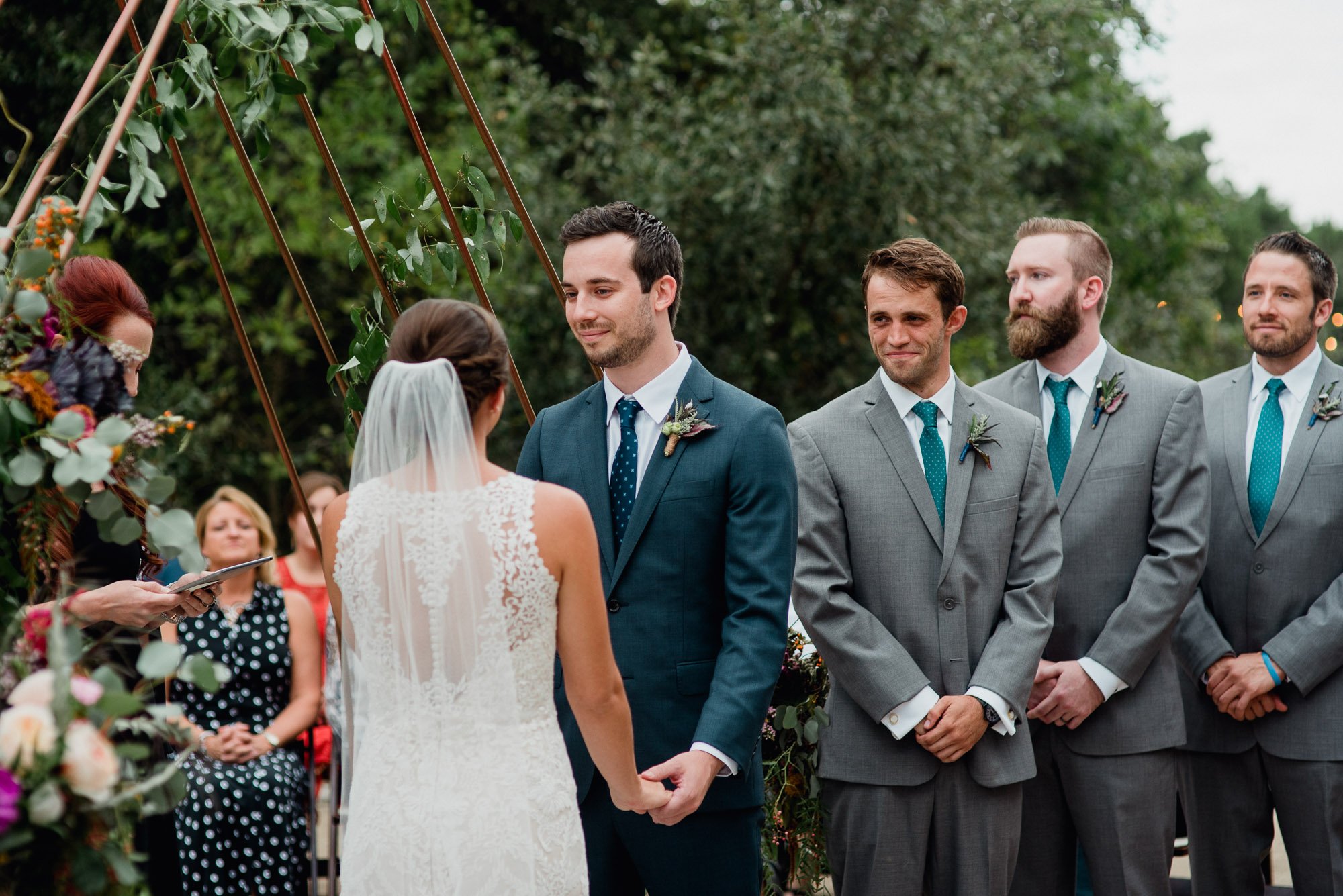 driftwood wedding photographer groomsmen smiles at bride during his best friend's wedding