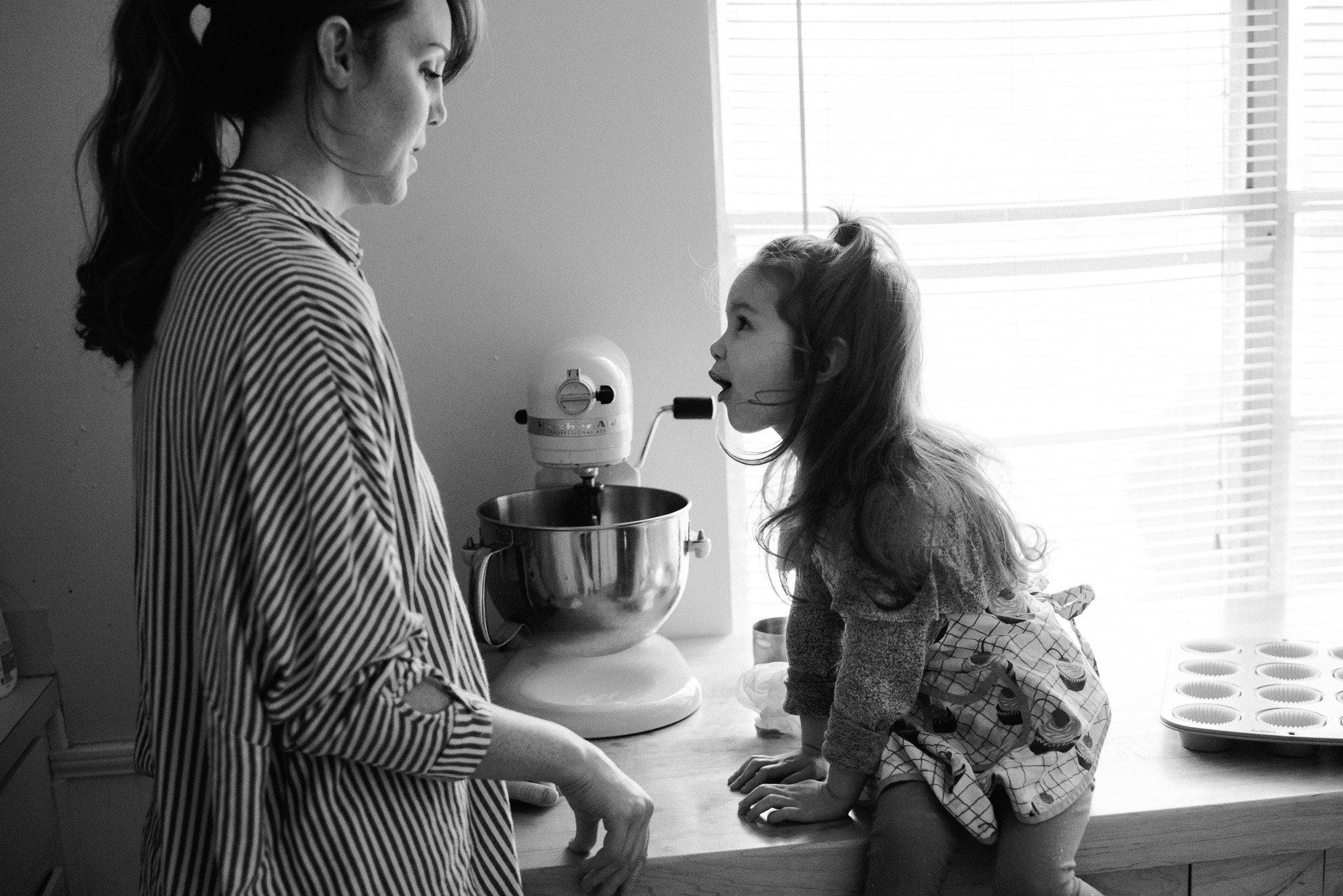 black and white candid shot of a mother and daughter baking