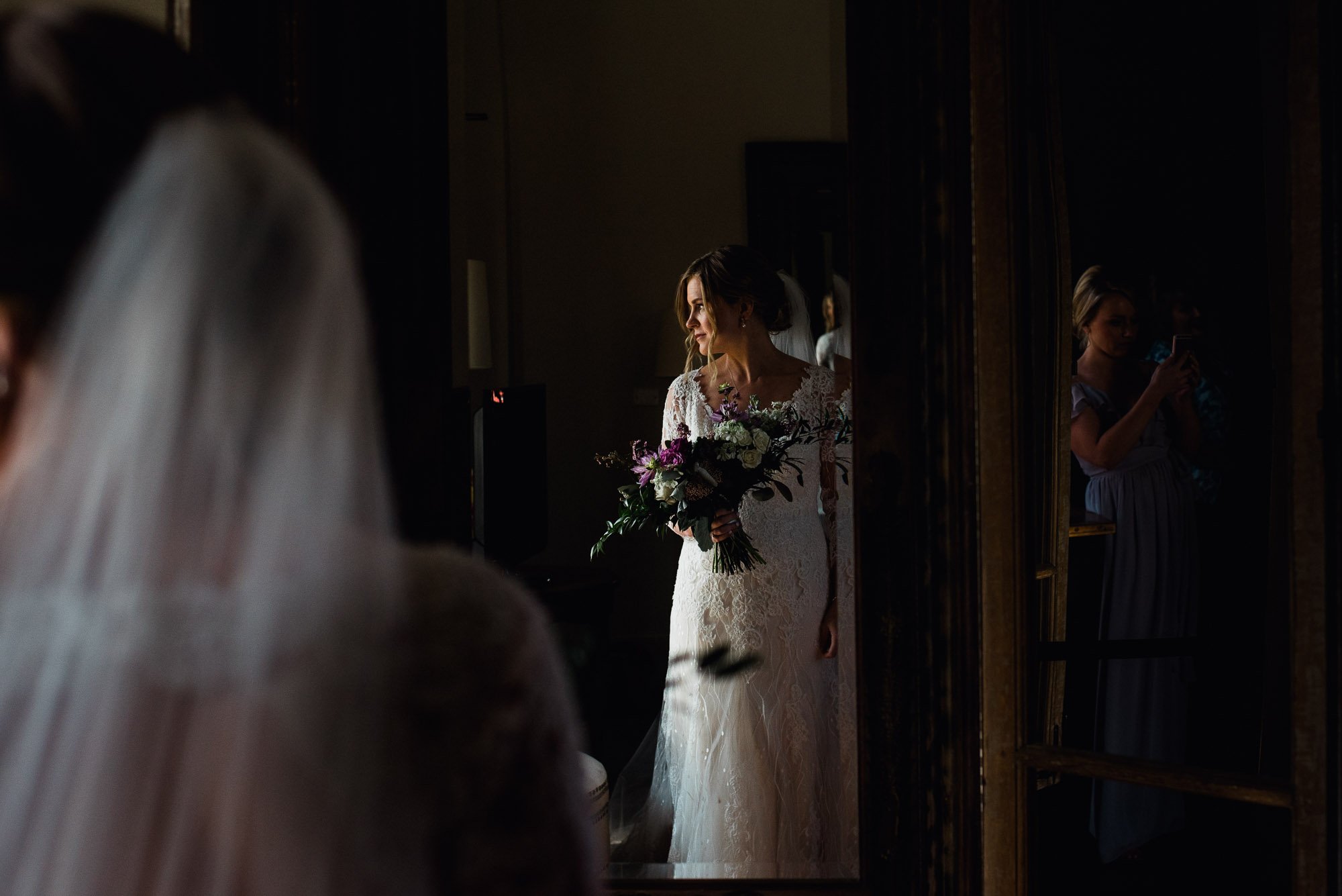 bride getting ready next to a big window at her henkel hall wedding, getting ready photographs