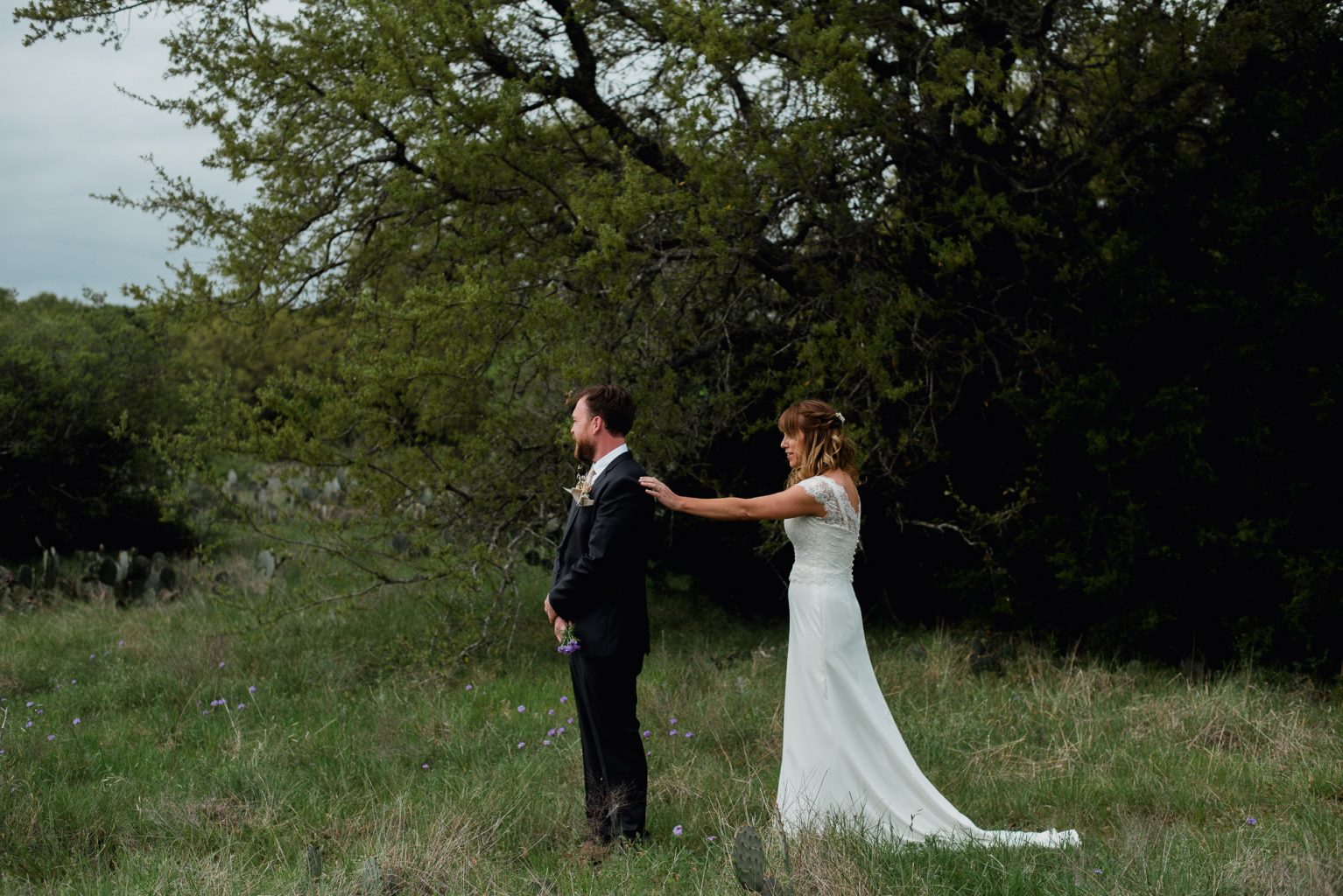 a bride in a white dress partakes in a first look with her future husband in a grey suit at the plant at kyle