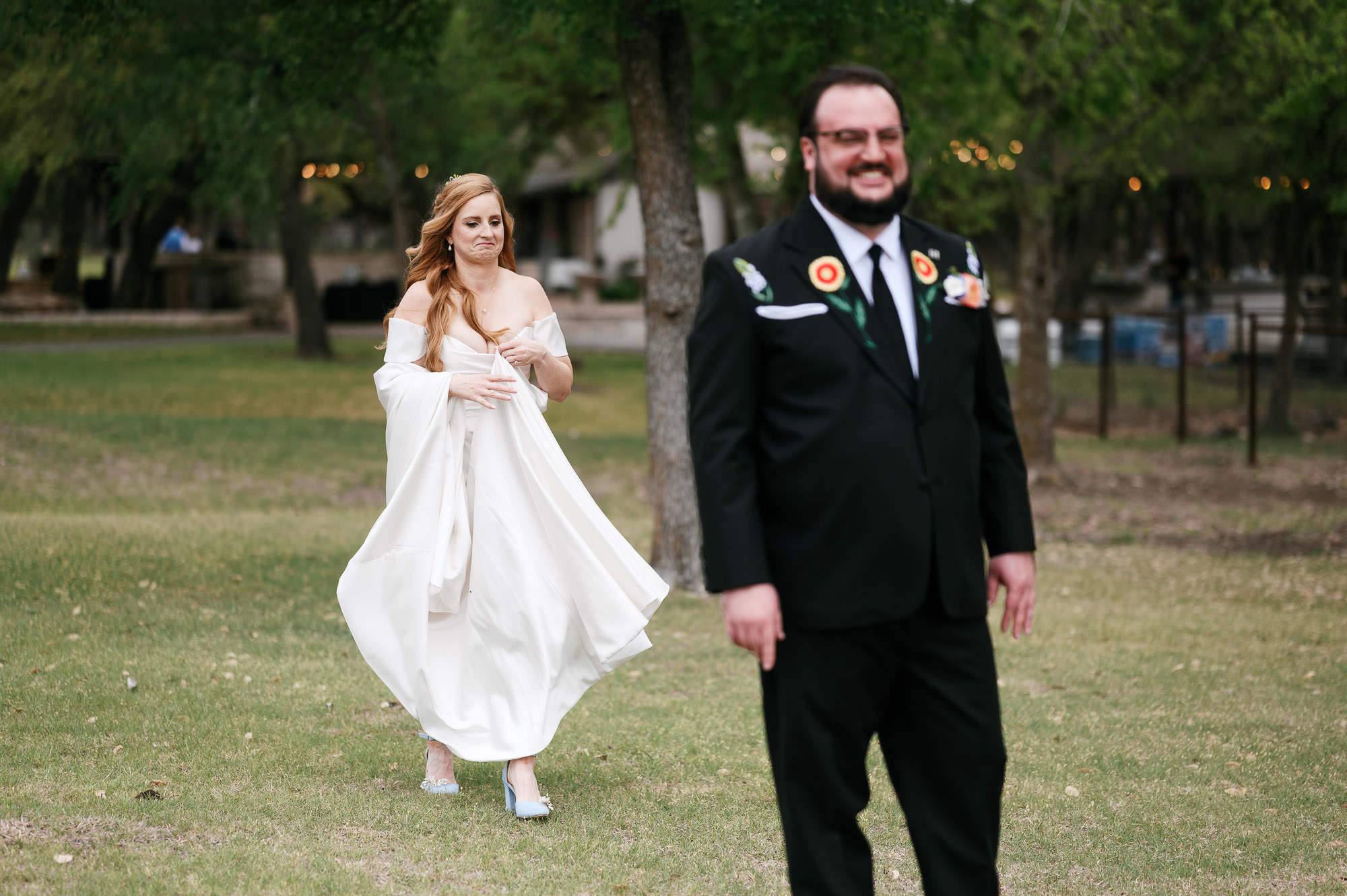 Groom, out of focus in foreground, smiles waiting for a first look at his spring wedding in austin